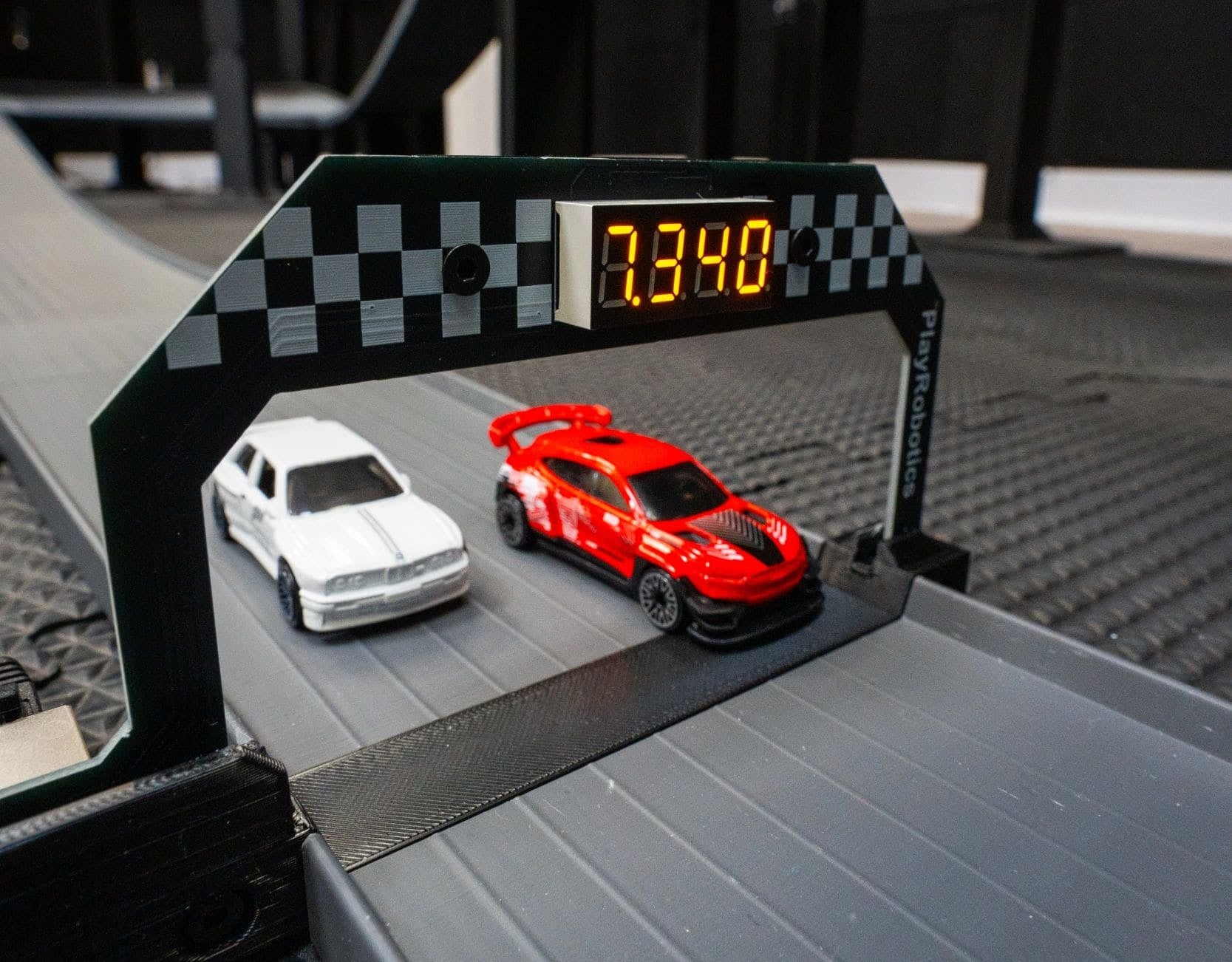 Two toy cars on a race track with a digital display showing time.